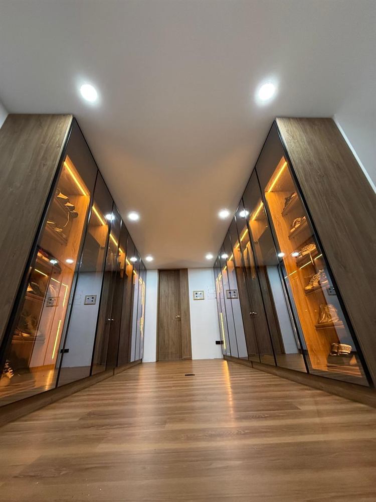 Vestier con puertas de vidrio y luz cálida a los lados de un pasillo