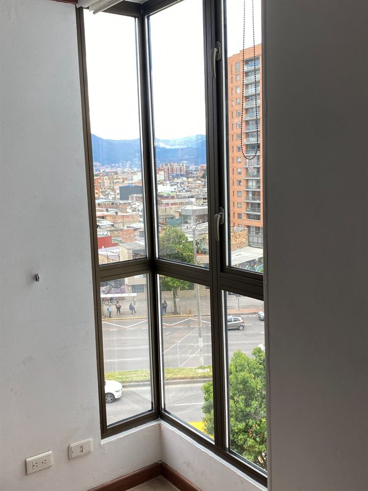 Ventana esquinera de marco negro con vista a los cerros de Bogotá